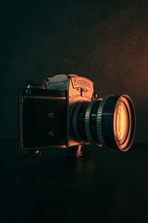 a lit up lens and an old camera sitting on a table