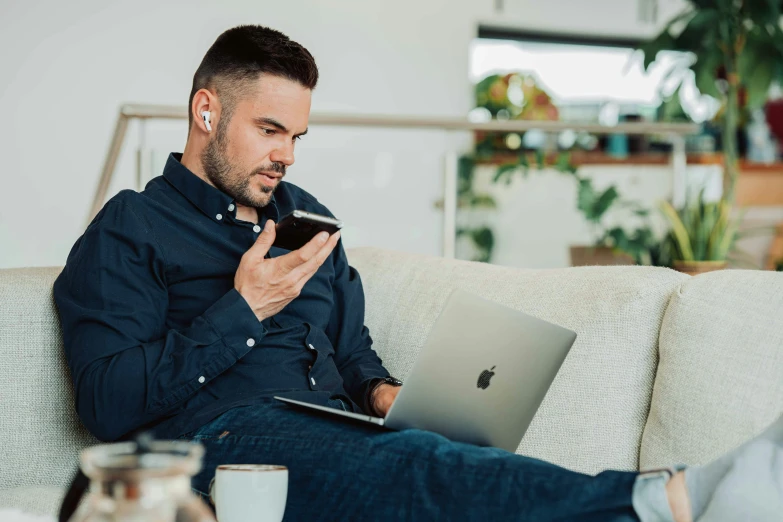 a man sitting on top of a couch next to a laptop computer