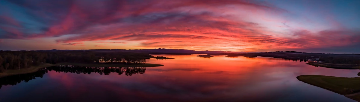 a view of the water, land, trees and a sky