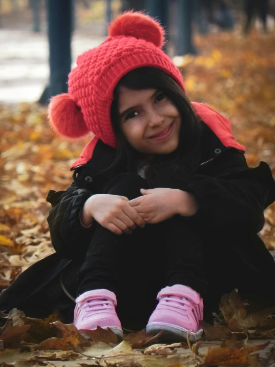 a  sitting in the leaves while wearing a red hat