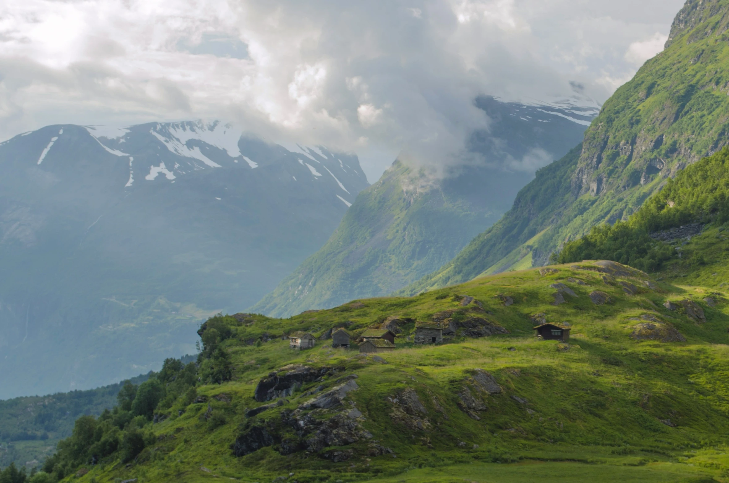 the green grassy valley in the mountains has a mountain range