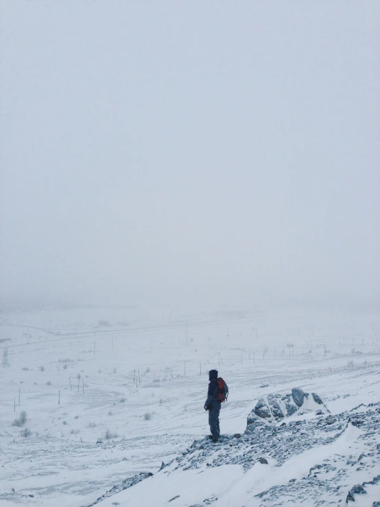 person walking uphill covered in snow, during winter