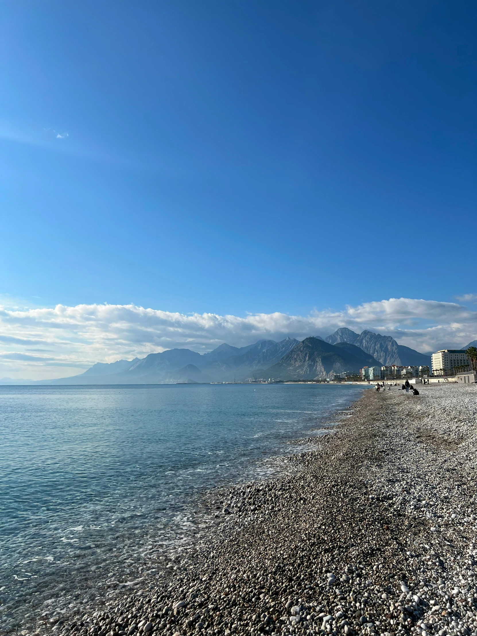 the beach in front of a mountain range with some very small houses