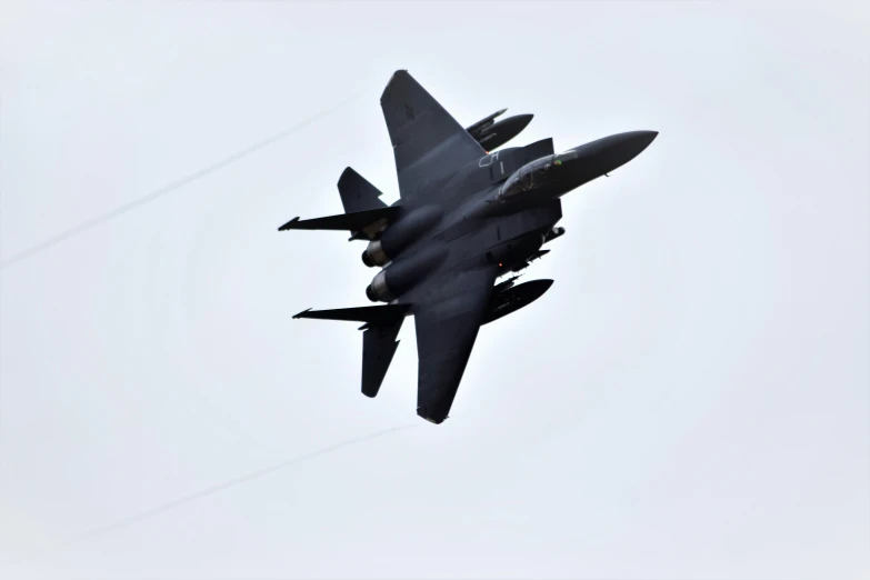 a fighter jet flies in the air as it passes through a power line