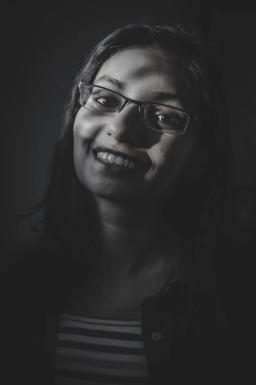 a close up of a woman wearing glasses in the dark