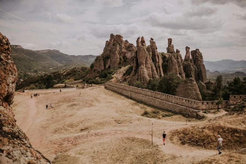 a rocky landscape with mountains and people walking on it