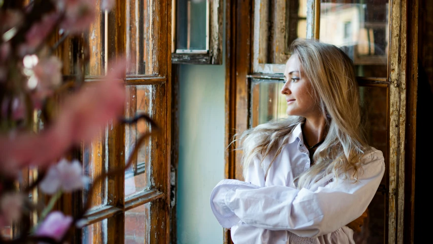 a woman looks outside through the windows of her house