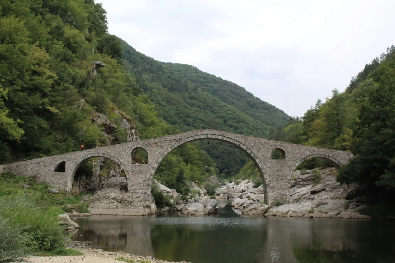 an old stone bridge surrounded by green mountains