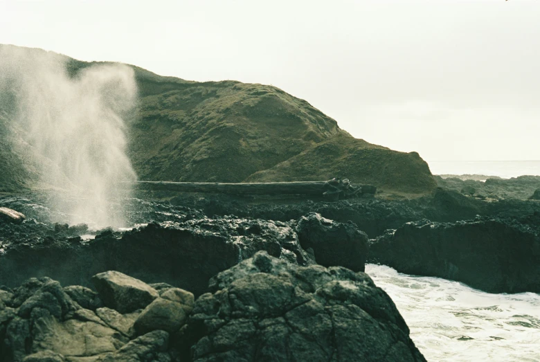 a white waterfall on rocks next to water