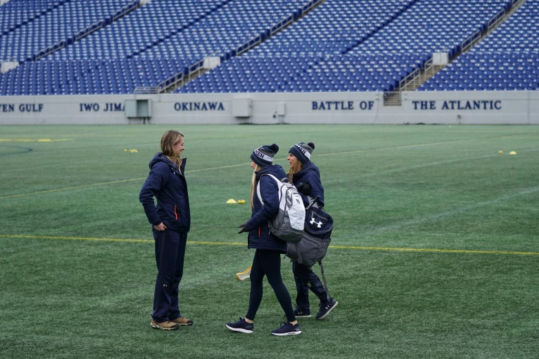 several people stand in a grassy field on a football field