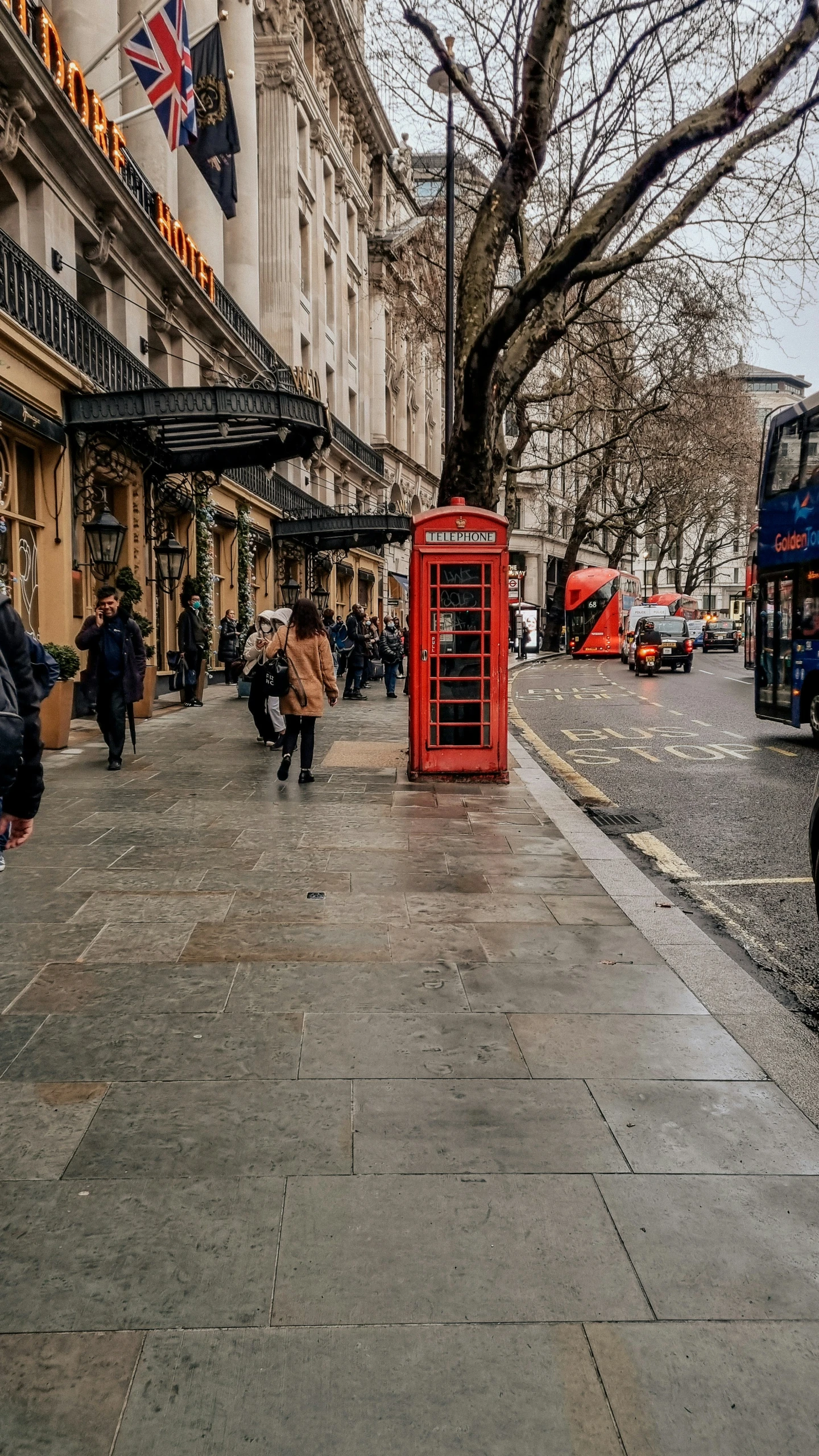 an old style red phone booth is on the sidewalk