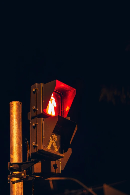 an illuminated traffic light sits with dark background