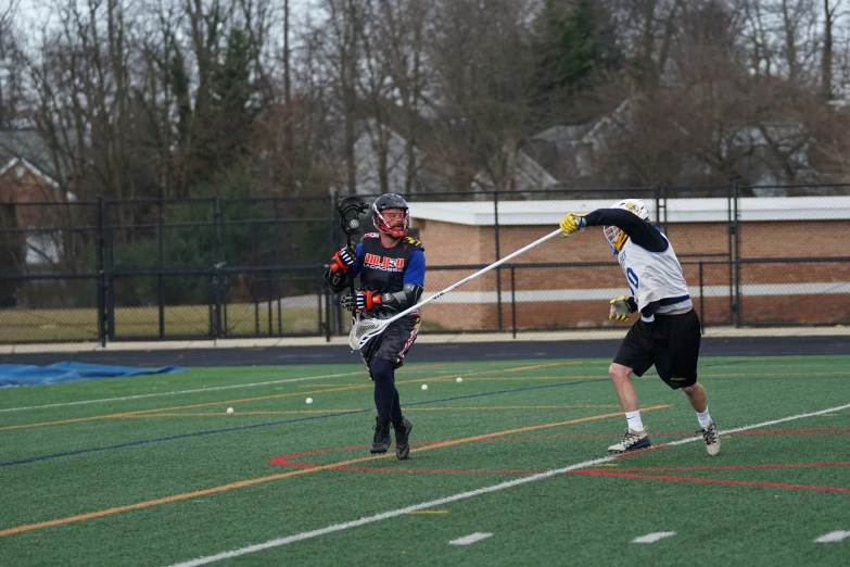 two people are playing lacrosse in a field