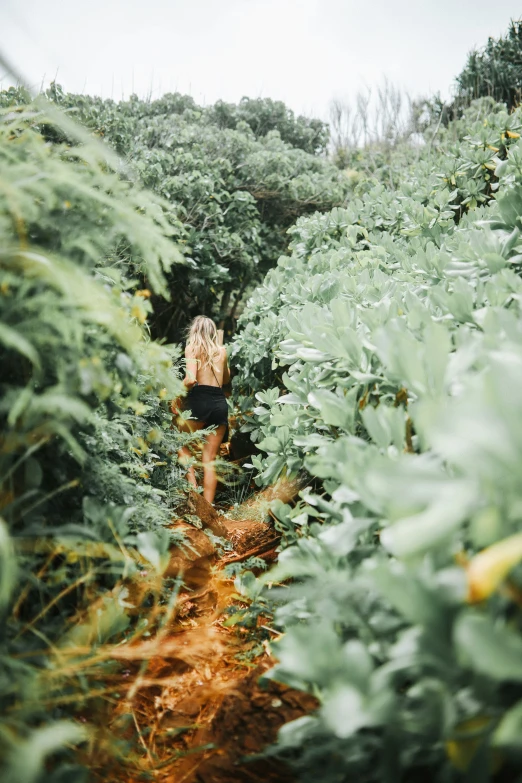 woman in swimsuit walking through trees and plants