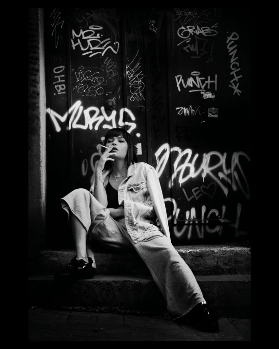 a woman in a dress sits on steps by a wall with graffiti