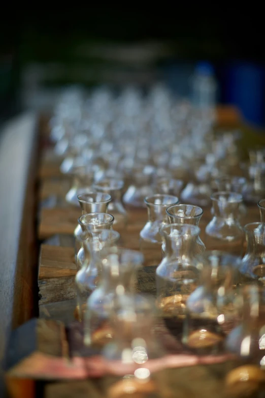 a large amount of glasses sit on a wooden table