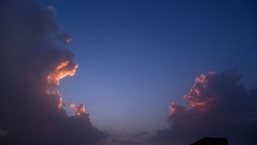 some pink clouds are on a blue sky