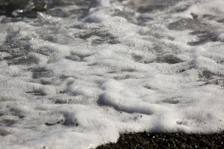 the water is churning over the black sand