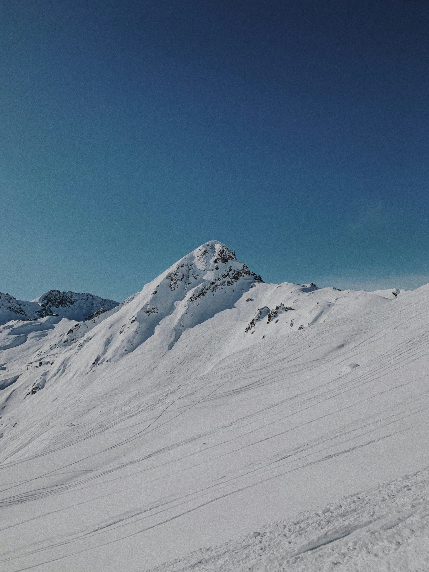 a skier in orange is skiing up a snowy mountain