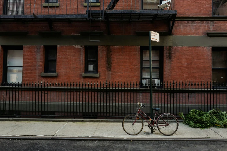a bike parked against a fence near an apartment building