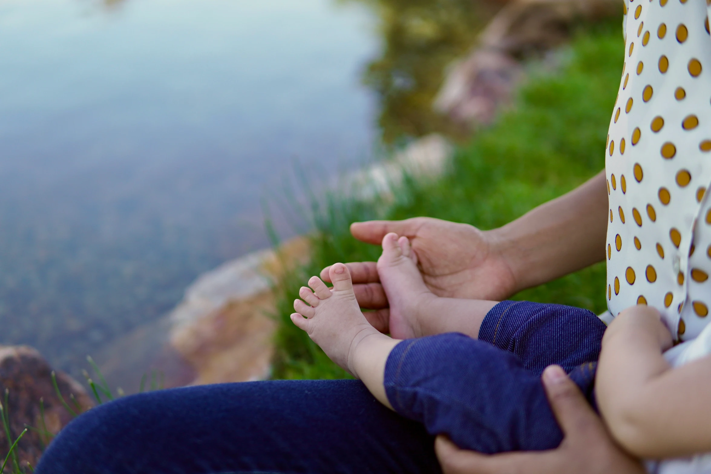 the person is holding the baby's feet next to the water