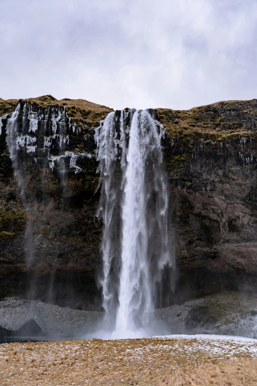 a large waterfall towering over a lake near a mountain