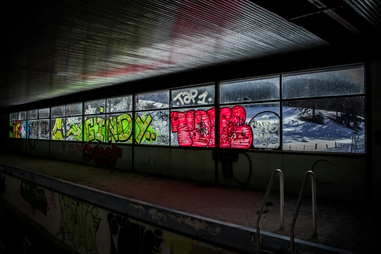 colorful graffiti is seen on windows at an abandoned subway station