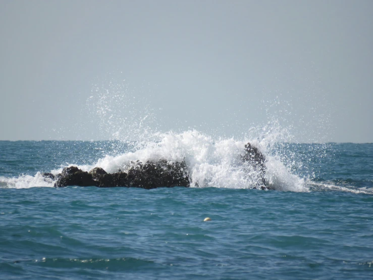 a water spray is splashing from the top of a rock into the ocean