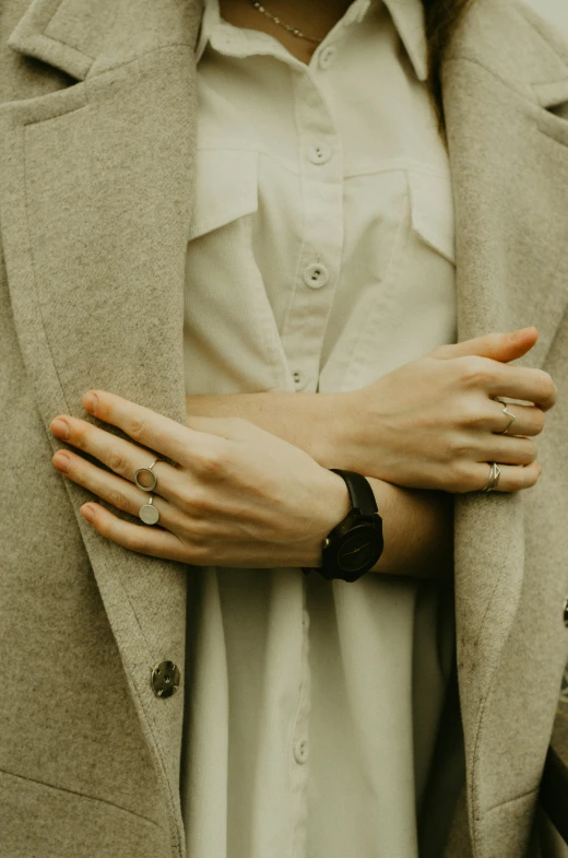 a woman wearing a tan coat with her hands folded out