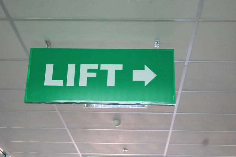 a green arrow sign sitting on top of a metal ceiling