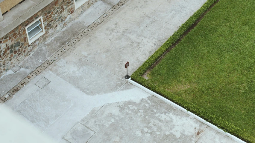 a man walking down a sidewalk next to a lush green field