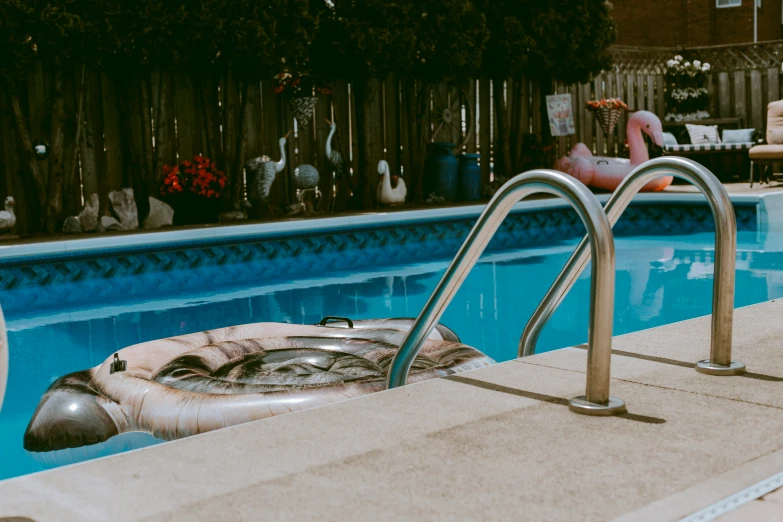 the pool with an inflatable mattress is next to a fence