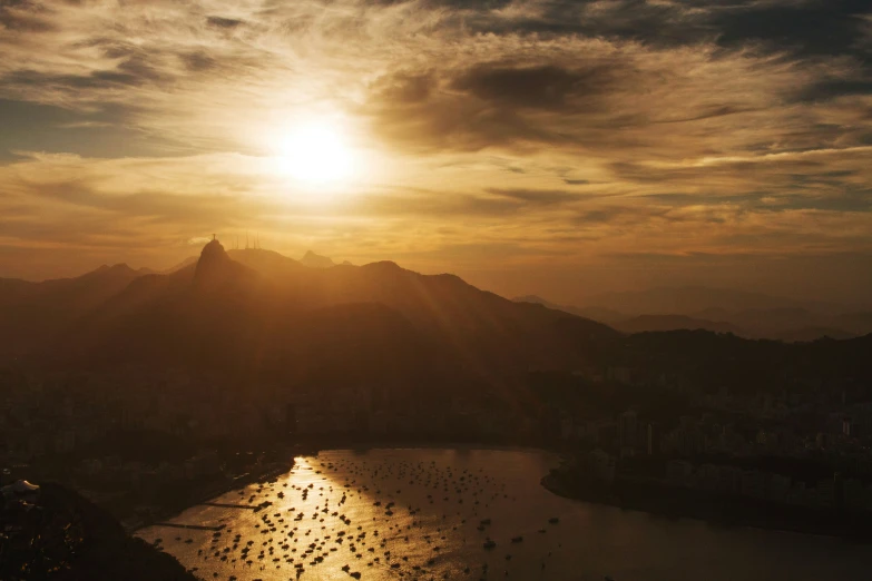 the sun set over some mountains over a body of water