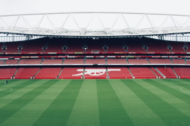 an empty stadium with red seats and grass