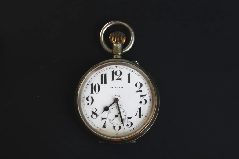 a small pocket watch sitting on a black surface