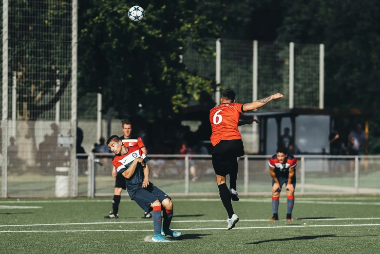 three men are playing soccer with one jumping high in the air