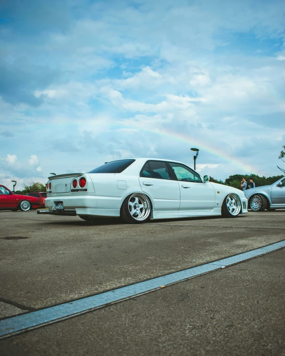 a white car sitting in a parking lot next to other cars