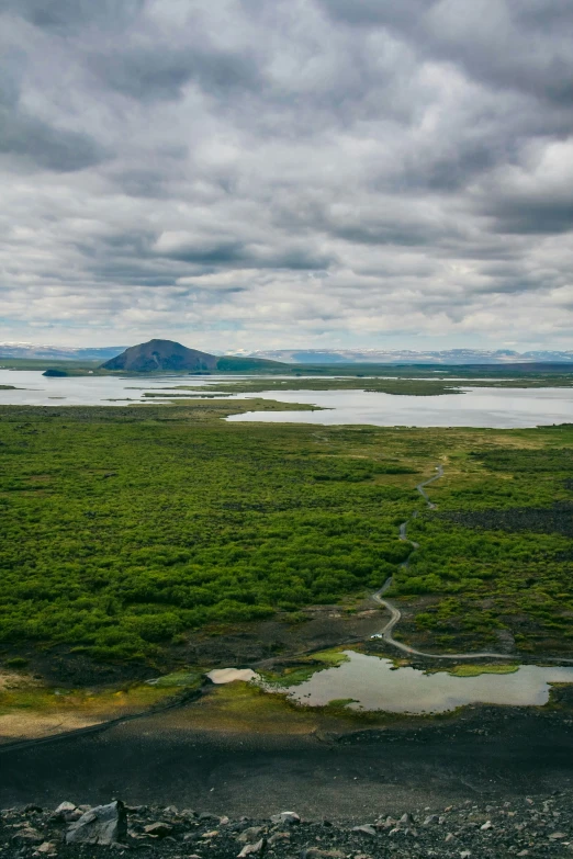 a lake sits in the middle of an open field with land in the foreground