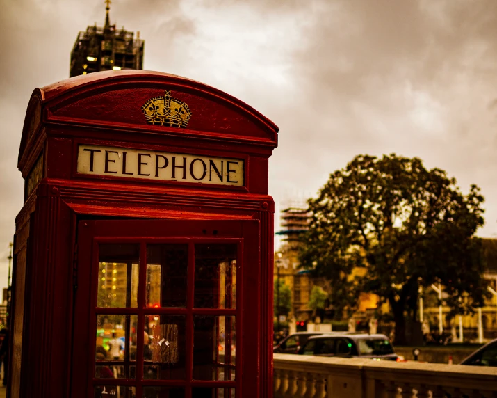 a telephone booth sits outside on a cloudy day