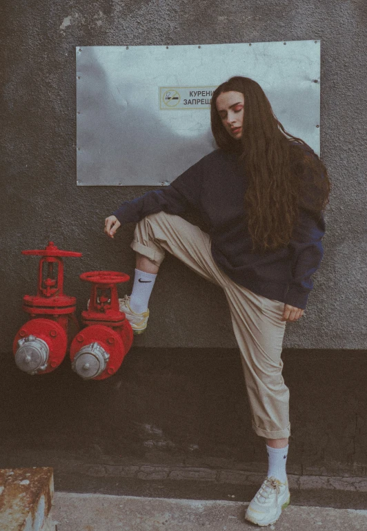 a woman leaning against the wall by some fire hydrants