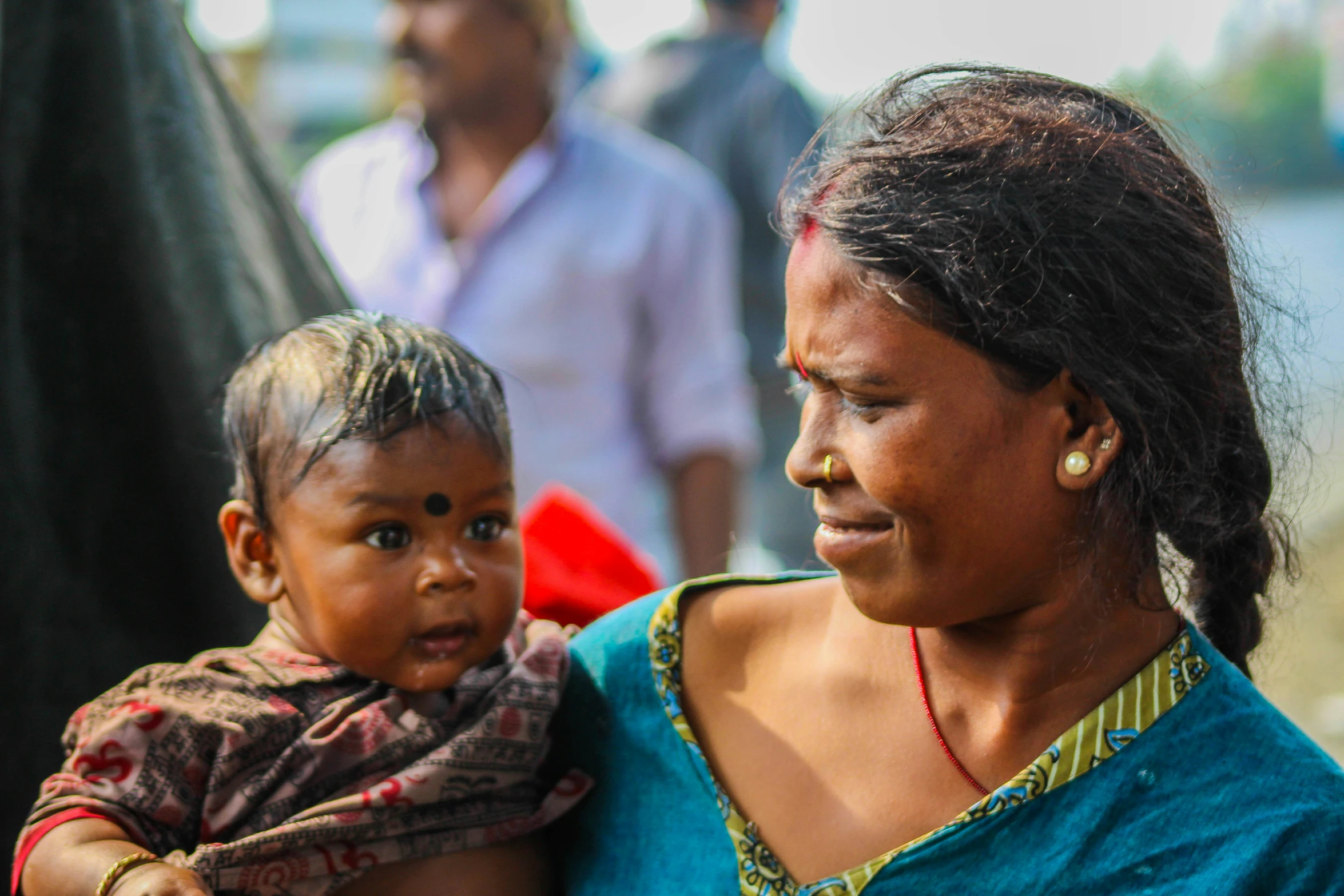 woman in an indian ethnic wear holds her child while she looks at another person