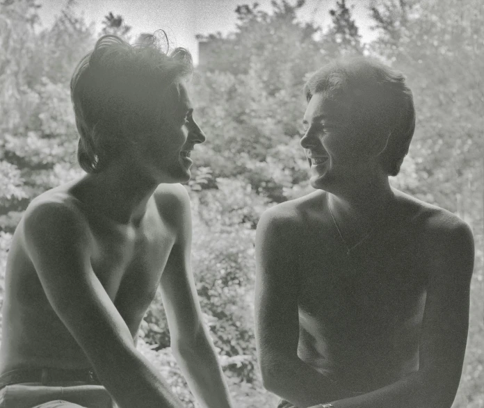 a couple of boys sitting on top of a wooden bench