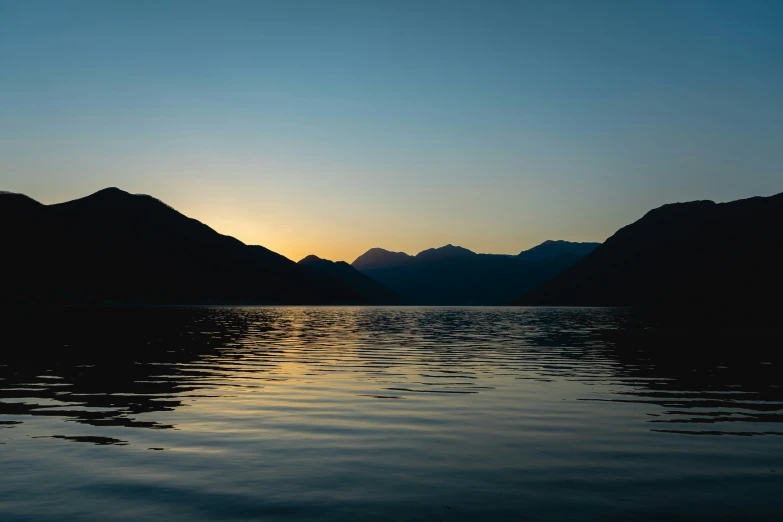 some very pretty mountains at sunset on a lake