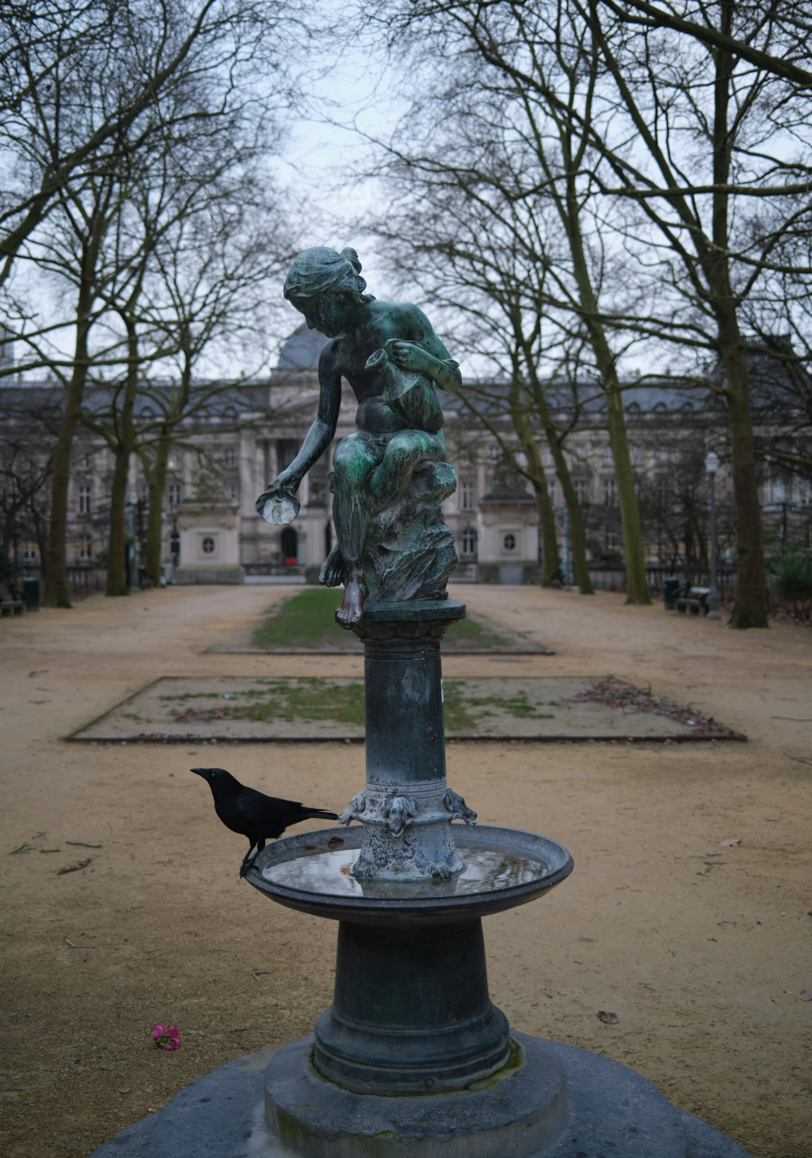 a bird sits on a fountain in the middle of an open field