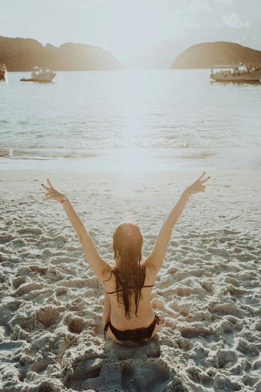 the girl is sitting in the sand on the beach