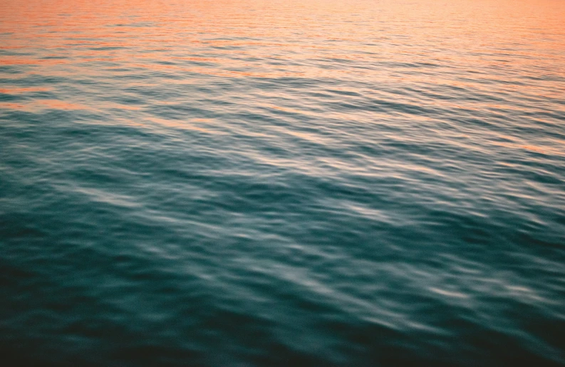 a calm sea with the sunset reflecting on the water