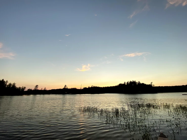 a boat is sailing on the lake during sunset