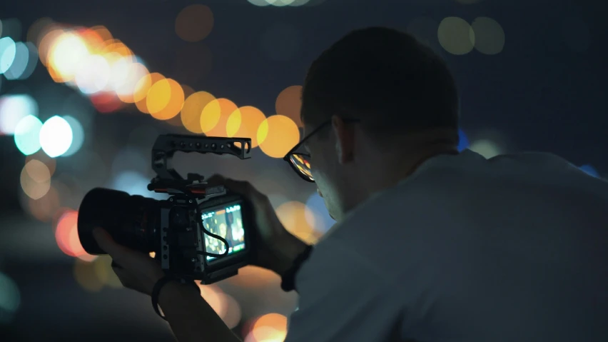 man holding video camera taking picture with blurry background