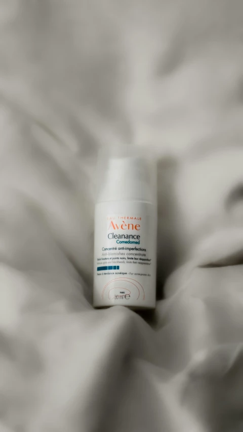 a white bottle of skin repair sitting on top of a bed