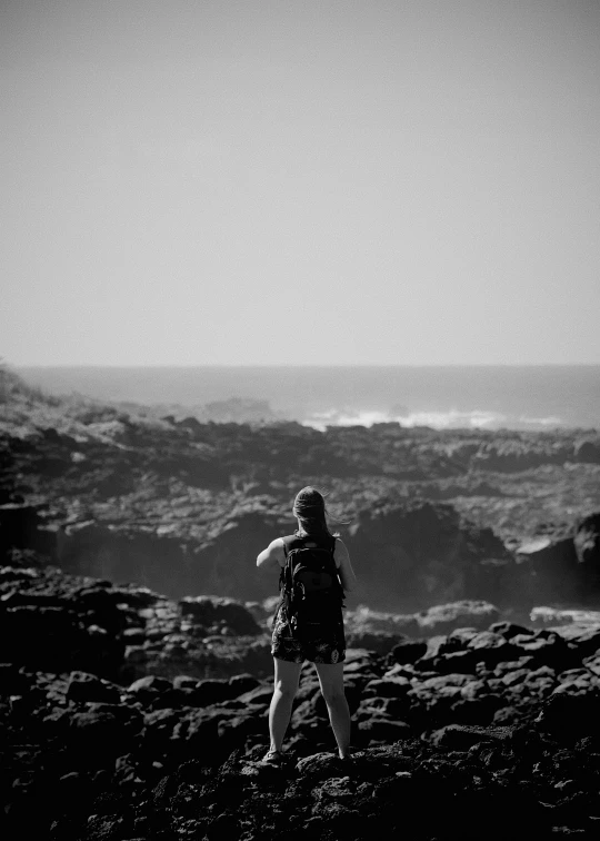 a person is standing on a rocky hill by the ocean